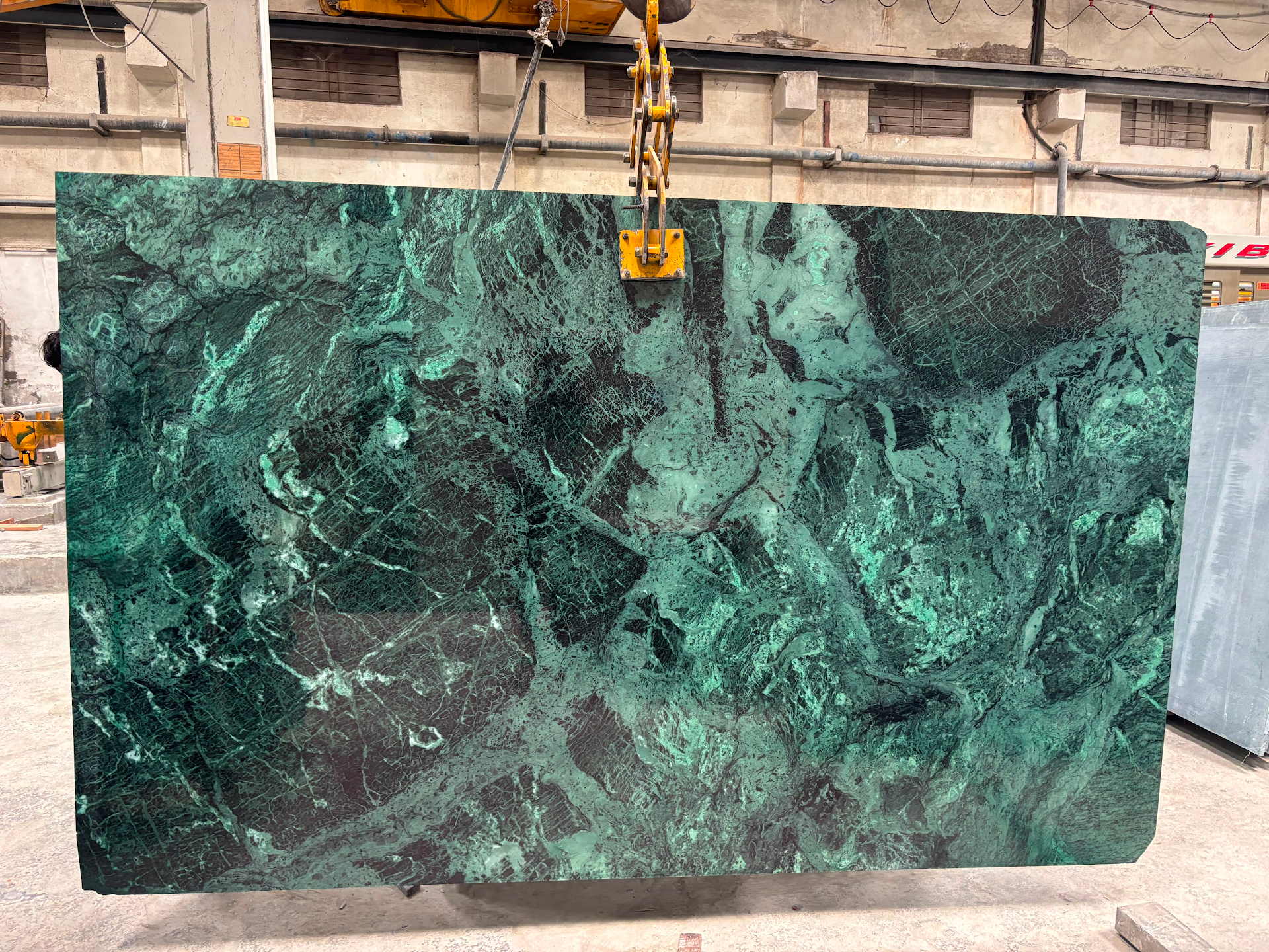 Placa de mármol verde suspendida de una grúa
